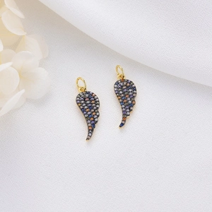 Detail of angel wing charms with purple and blue zircon stones on white fabric