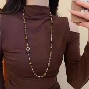 Detail einer Vintage-Halskette mit Tigerauge und Perlen getragen mit elegantem Outfit