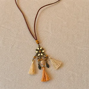 Détail du pendentif fleur ethnique avec perles en bois et triple glands en fil sur lin