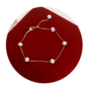 Elegant gold chain bracelet featuring white freshwater pearls on a luxury red velvet base