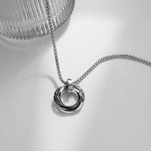 Close-up of interlocking silver and gunmetal rings on a premium textured surface