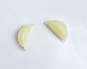 Detailed close-up of two miniature translucent yellow dumpling wax crafts on white background