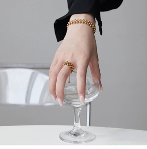 Detail of 18K gold-plated beaded bracelet and ring set held with an elegant glass