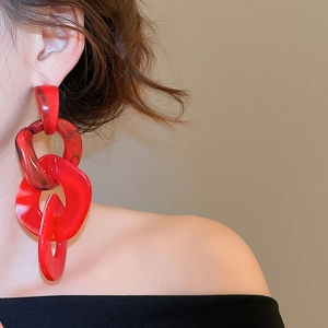 Detailed view of red acrylic chain earrings with marble texture worn by a model
