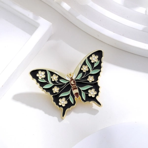 Detailed view of enamel butterfly brooch with gold edges and floral patterns