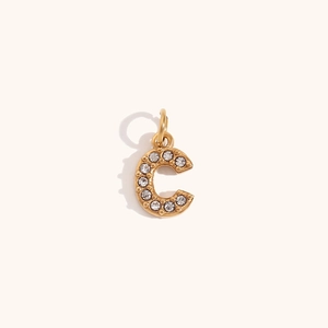 Detalle de un colgante letra C bañado en oro de 18K con brillantes de imitación