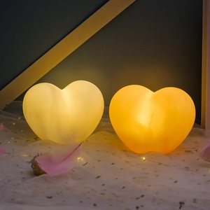 Close-up of heart-shaped night lights with soft warm orange glow on starry fabric