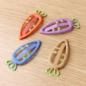 Set of four colorful carrot-shaped candy-colored hair clips on a wooden surface