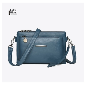 Detail of lake blue crossbody bag showing multi-pocket zippers and metallic hardware