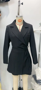 Detail of black long-sleeved blazer dress featuring a deep V-neck and side waist tie