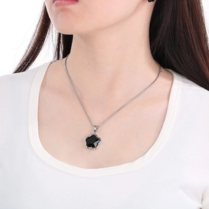 Close-up of a silver snake chain necklace with a black four-leaf clover pendant on model