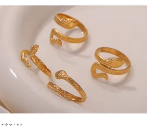Detailed close-up of four gold-plated snake-shaped textured rings on a white plate