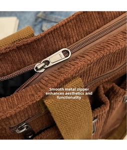 Detailed macro view of high-quality silver YKK zipper on a brown corduroy shoulder bag