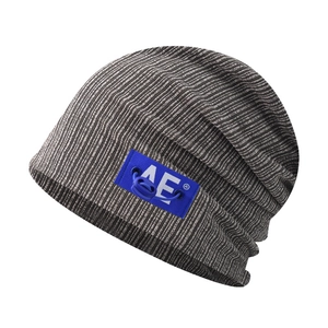 Detail of grey striped knit beanie featuring a blue AE logo label and drawstring toggle