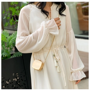 Mini golden acrylic evening bag with chain strap styled on a white summer dress