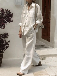 Detail of white linen-textured long-sleeve shirt and wide-leg trousers on model