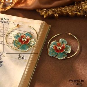 Macro detail of large gold hoop earrings with vintage green enamel flower pendants