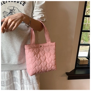 Detailed view of pink heart-quilted nylon fabric with a soft puffy texture on handbag
