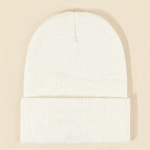 Detail of white knit beanie showing vertical ribbed texture and wide folded cuff design