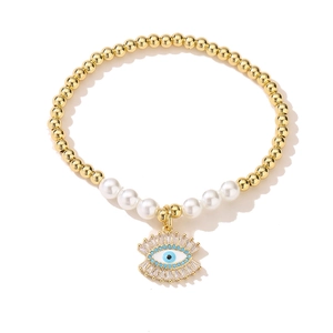 Detail of 18K gold plated beaded bracelet with evil eye charm and white pearls
