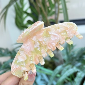 Dettaglio molletta per capelli in acetato rosa pesca e giallo con raffinato effetto marmo