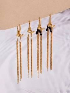 Detail of gold tassel earrings with black and white enamel charms on a display card