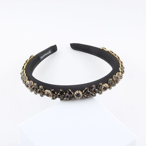 Detail of handmade baroque headband with black crystals and gold metal settings on satin