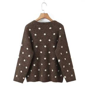 Dettaglio del pesante maglione in maglia marrone a pois bianchi con consistenza soffice