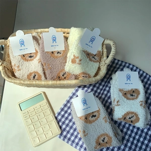 Detail of warm coral fleece socks with cute bear patterns and retail card packaging