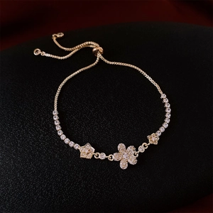 Detail of a gold floral bolero bracelet with sparkling cubic zirconia on a black texture