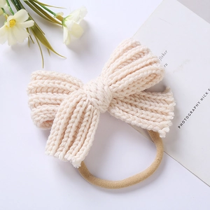 Close-up of a cream-colored knit bow headband for newborns with high elastic soft nylon band