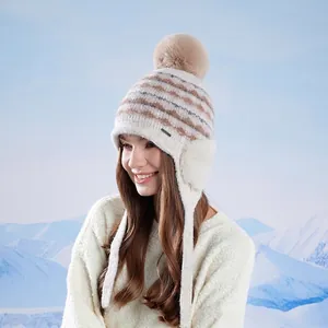 Bonnet tricoté pour femme avec protège-oreilles et pompon en fausse fourrure sur fond de neige