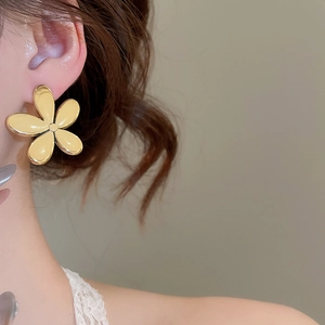 Vue détaillée de boucles d'oreilles fleur dorées portées par un mannequin