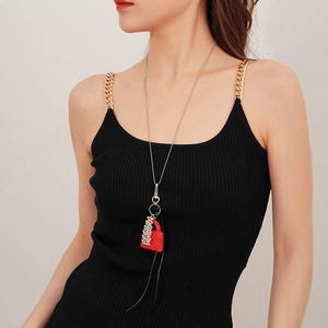 Vue détaillée d'un pendentif sac rouge étincelant sur une longue chaîne porté par un mannequin