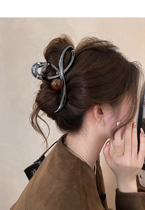 Detail view of a gunmetal hair claw with amber marble ball on a female model