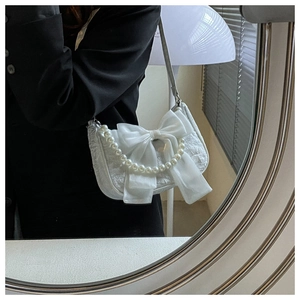 Close-up of white jacquard bag featuring a large satin bow and elegant pearl handle strap