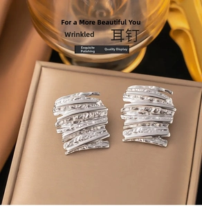 Macro view of silver hammered texture stud earrings with irregular folded metal design
