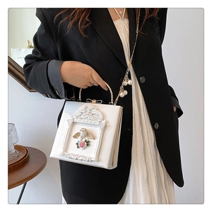 Close-up of white Baroque embossed angel and pink rose details on women's handbag
