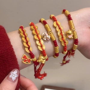 Macro view of woven red rope bracelet featuring gold charms and enamel horse pendant