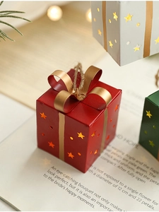 Gros plan sur un mini coffret cadeau rouge avec étoiles ajourées et ruban doré de Noël