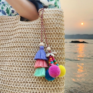 Bohemian bag charm with colorful tassels, pom-poms and shells on a straw bag
