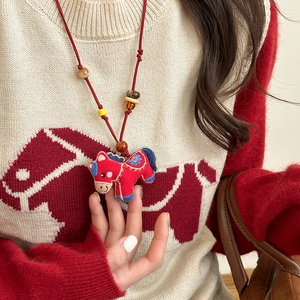 Close-up of red embroidered horse pendant with colorful beads on a red woven necklace