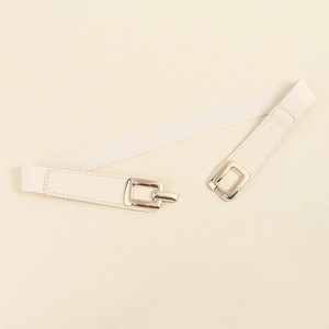 Detail of cream elastic waist belt featuring a gold square metal buckle on a beige background