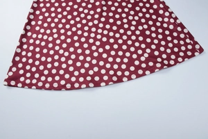 Close-up of the wine red polka dot dress hem showing high-quality stitching and fabric