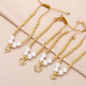 Gold-plated beaded bracelets with heart, crown and butterfly charms on pink silk
