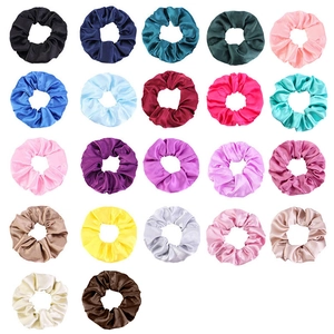 Flat lay of 22 assorted colorful satin hair scrunchies on a white background