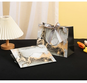 Detail of luxury marble texture paper gift bag with golden accents and silk ribbon bow