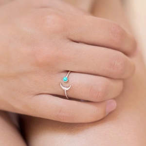 Adjustable silver crescent moon ring with turquoise bead shown on a finger