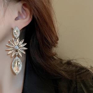 Close-up of oversized silver flower earrings with crystal petals worn by a model