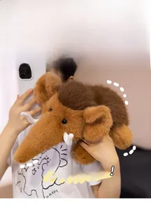 Detail of soft brown mammoth plush toy with long tusks being held by a model